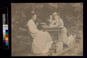 [Two women sitting outside at table drinking wine and beer]