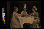 [Three women sitting at table toasting with wine glasses]