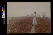 [Woman holding child looking at field]