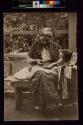 [Woman sitting on bench holdng coins]