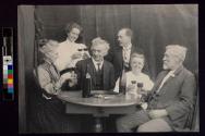 [Six people around table toasting with wine glasses]