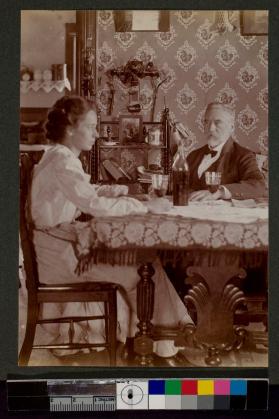 [Woman and man sitting at table with wine]
