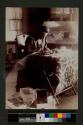 [Woman sitting and making rug]