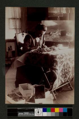 [Woman sitting and making rug]