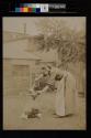 [Woman standing over fire holding chicken]