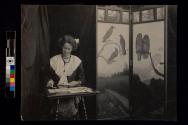 [Woman sitting at desk playing cards]