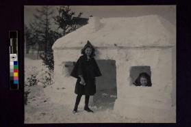 [Two girls standing outside of snow fort]