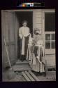 [Woman selling lace to woman standing in doorway]