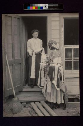 [Woman selling lace to woman standing in doorway]
