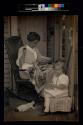 [Woman sewing and girl sitting on porch]