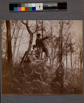 [Man standing at top of mound pointing with three people around him]