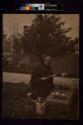 [Woman kneeling in cemetery reading book]