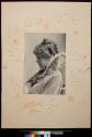 [Young woman in cape with appliqué on collar, mounted on board that has been incised in floral design]