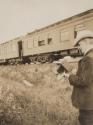 George Eastman with camera beside train, Western Trip