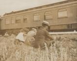 Mulligans and Walter Hubbell in grass near train, Western Trip