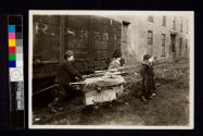 [Children pulling wagon loaded with scrap wood]