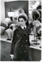 [Woman in front of hat display]
