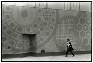 [Man walking beside mural]