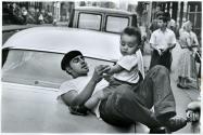 [Man with toddler on the hood of a car]