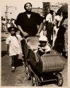 [Family walking down street with buggy]