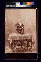 [Dwarf seated in chair on top of table]