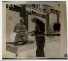[Woman at photo products table with Photographic Society member]