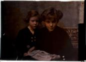 [Two seated children with picture book]