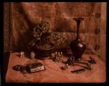 [Still life study with Japanese netsuke, bonsai tree, comb, candle-snuffer, "inro", vase and other small objects]