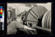 [Man at machine manufacturing large electric motor]