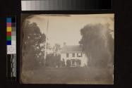 [Stucco house, woman and child in doorway]