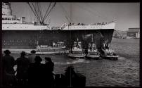 [Tugs berthing the 81,237-ton "Queen Mary," the largest passenger liner of her day]