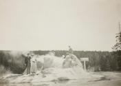 [Three people posing on the Grotto Geyser in Yellowstone National Park]