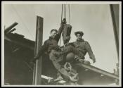 [Men on hoisting ball]