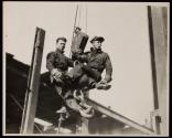[Men on hoisting ball]