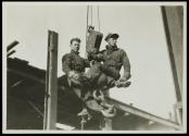 [Men on hoisting ball]