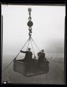 [Two men in derrick lift]