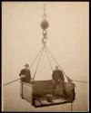 [Two men in derrick lift]