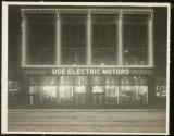 [Illuminated building, night scene with "Use Electric Motors" sign]