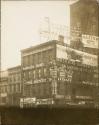 [Building covered with hand-painted advertising, illuminated sign on roof]