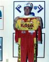 Jim Kelly posing with a signed uniform of Ernie Irvan