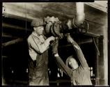 [Plumbers fitting pipes in office building.]