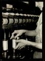 [Worker tending spools in textile mill]