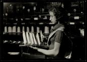 [Woman textile worker with spools of thread]