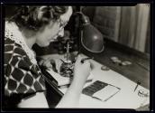 [Woman watch-maker testing the strength of hairsprinhgs and their relationship to the weight of the balance wheel.]