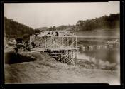 [Men framing building along river]