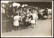 [Adults and children waiting in line]