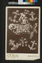 [Cabinet photograph of man displayed amongst funerary wreaths]