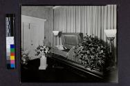 [Man laid out in velvet-lined coffin]