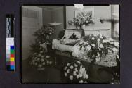 [War veteran in floral-patterned casket]