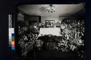[Woman laid out in room filled with flowers]